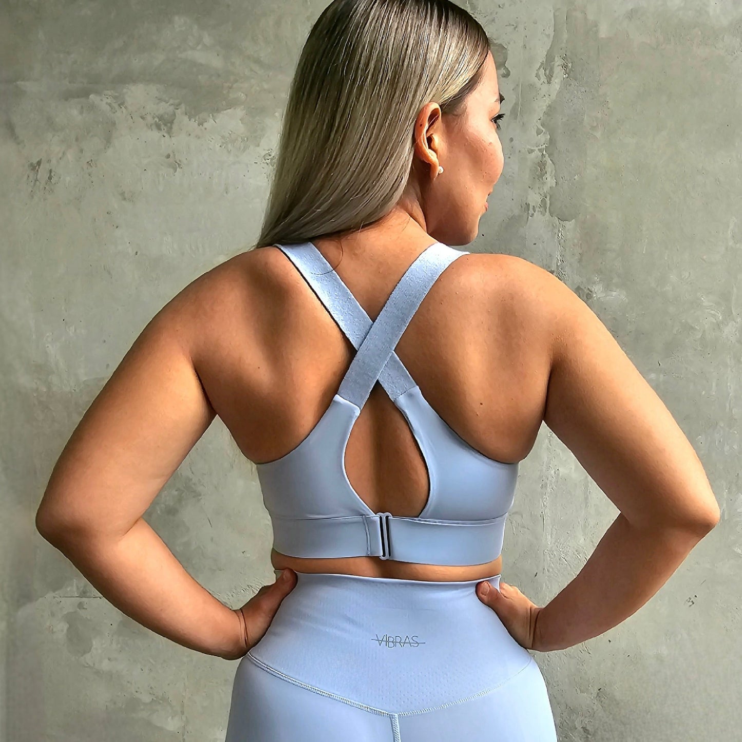 Back view of a Fitness model wearing a maximum support sports bra in the colour baby blue from Vibras Activewear.