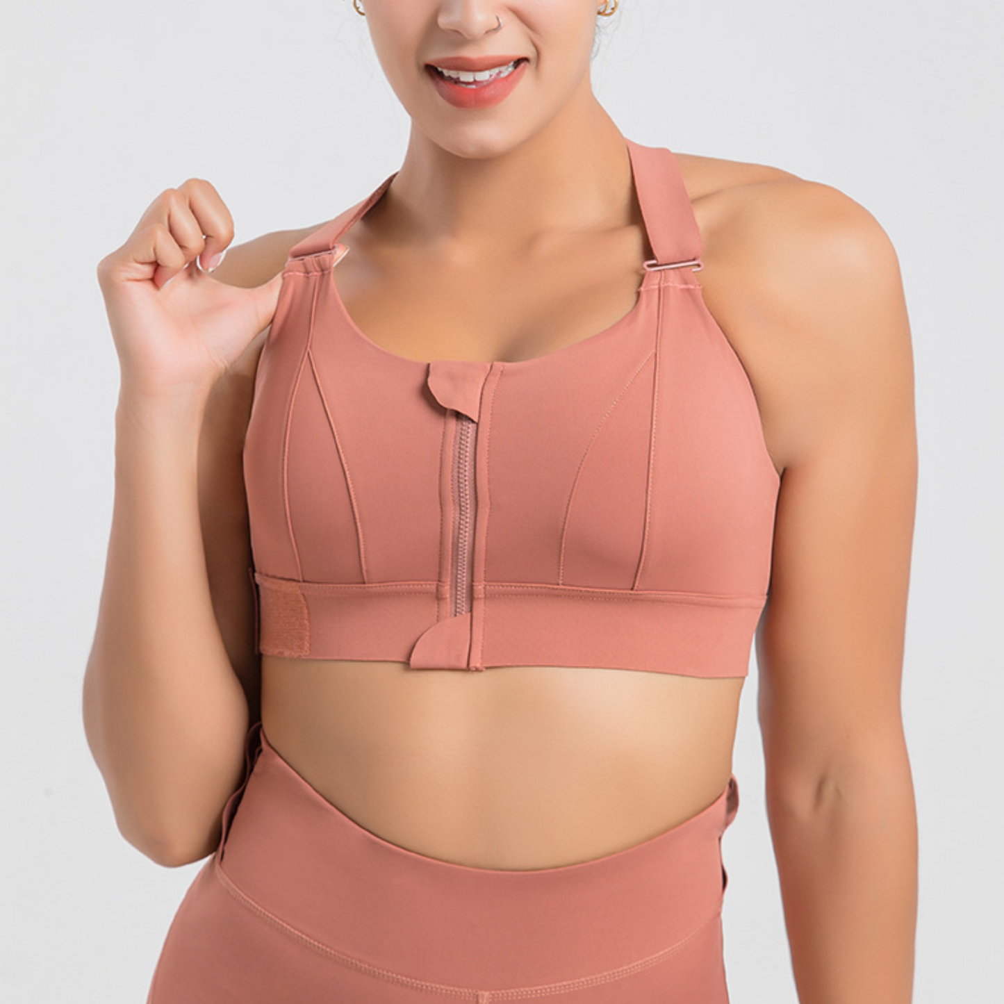 FITNESS MODEL wearing a terracota, high impact workout bra with straps that can be adjusted on the body.