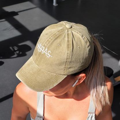 FITNESS MODEL WEARING A TAN BASEBALL CAP FROM VIBRAS ACTIVEWEAR AT THE GYM.