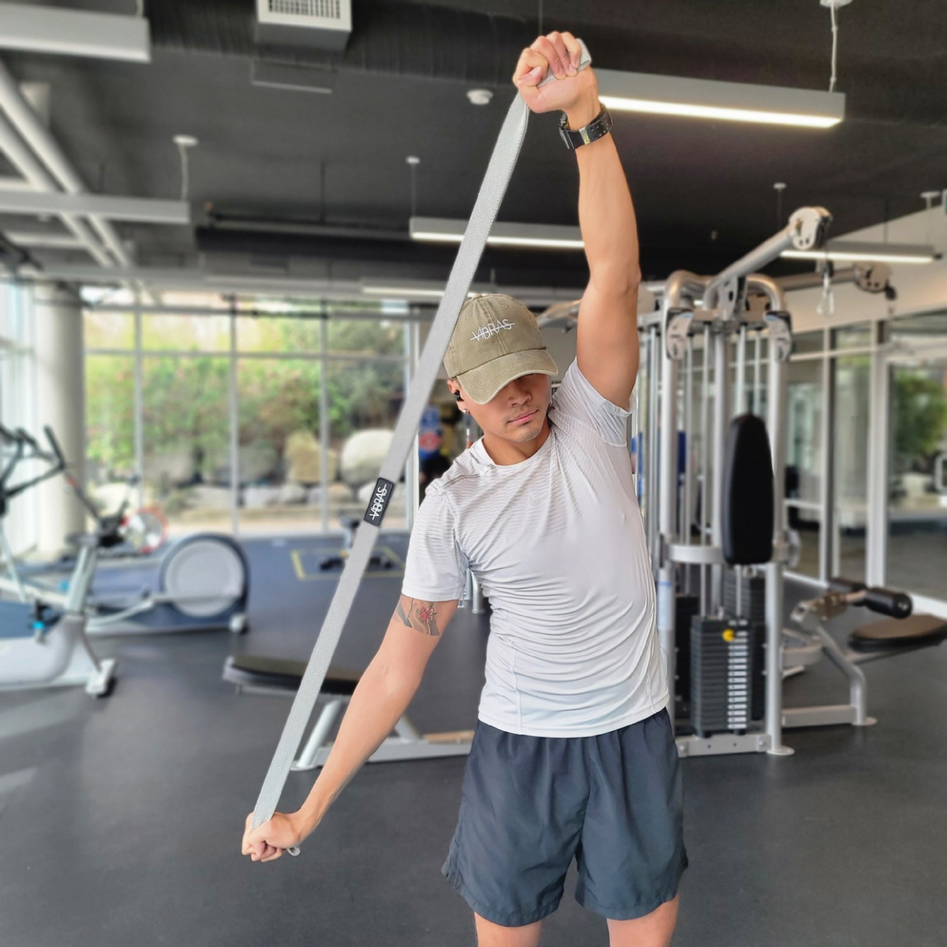 man using long resistance bands from vibras activewear at the gym to stretch his upper body 