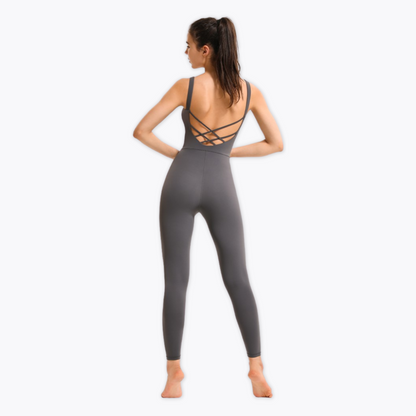 BACK SHOT OF MODEL WEARING A GREY JUMPSUIT FROM VIBRAS ACTIVEWEAR ON A WHITE BACKGROUND.