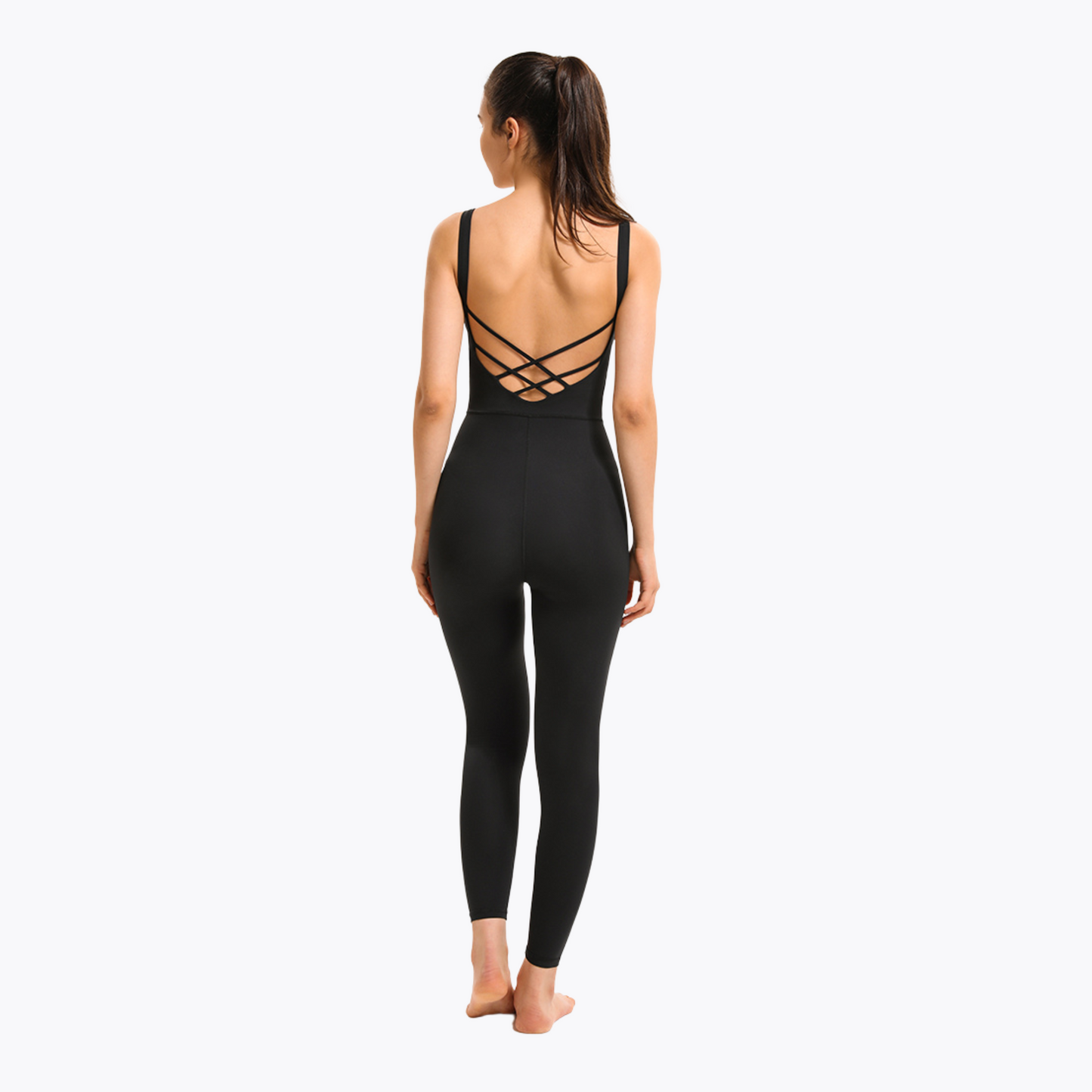 BACK SHOT OF MODEL WEARING A BLACK JUMPSUIT FROM VIBRAS ACTIVEWEAR ON A WHITE BACKGROUND.