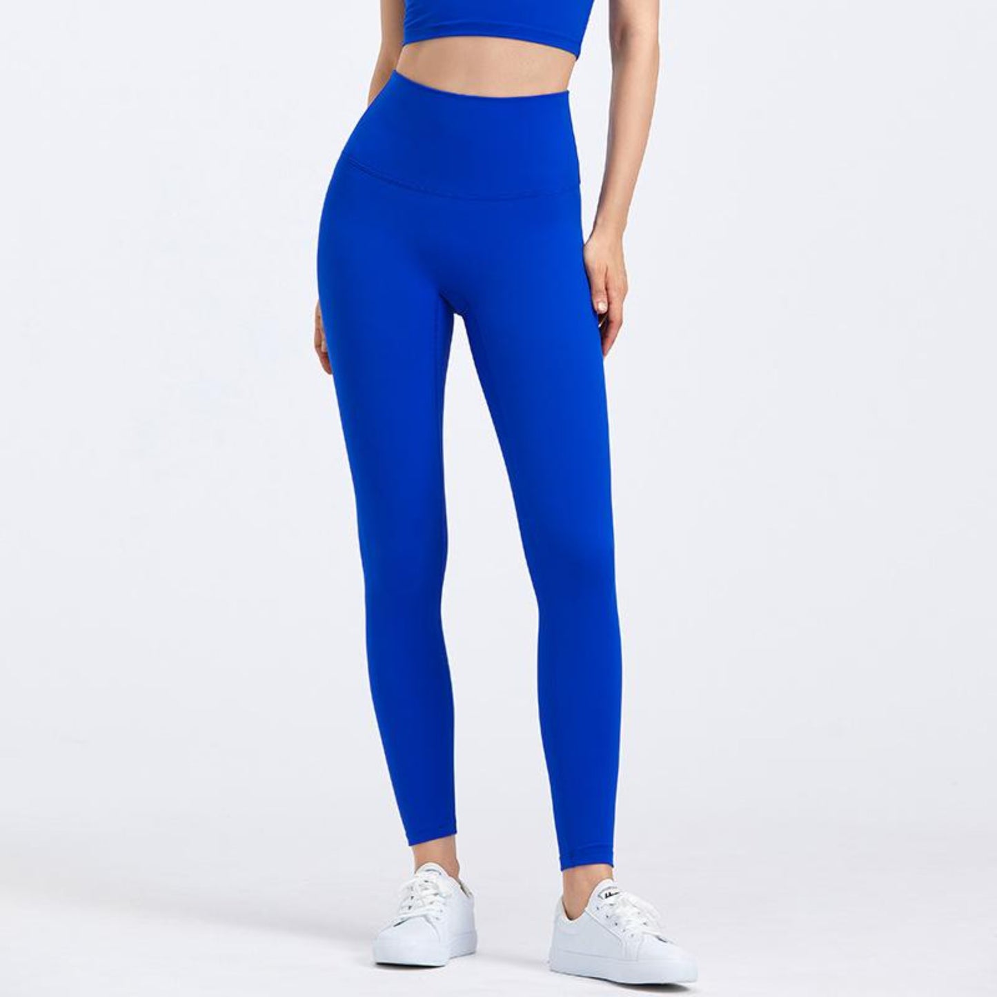 ELECTRIC BLUE, HIGH RISE AND SQUAT PROOF LEGGINGS WORN BY MODEL ON A WHITE BACKGROUND
