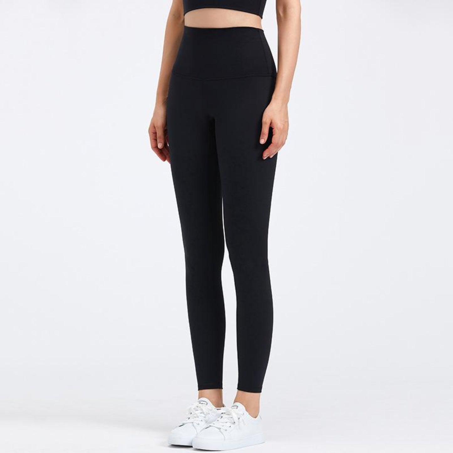DEEP BLACK, HIGH RISE AND SQUAT PROOF LEGGINGS WORN BY MODEL ON A WHITE BACKGROUND