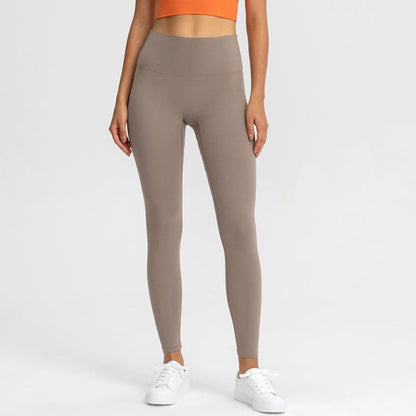 CARAMEL COLOURED, HIGH RISE AND SQUAT PROOF LEGGINGS WORN BY MODEL ON A WHITE BACKGROUND