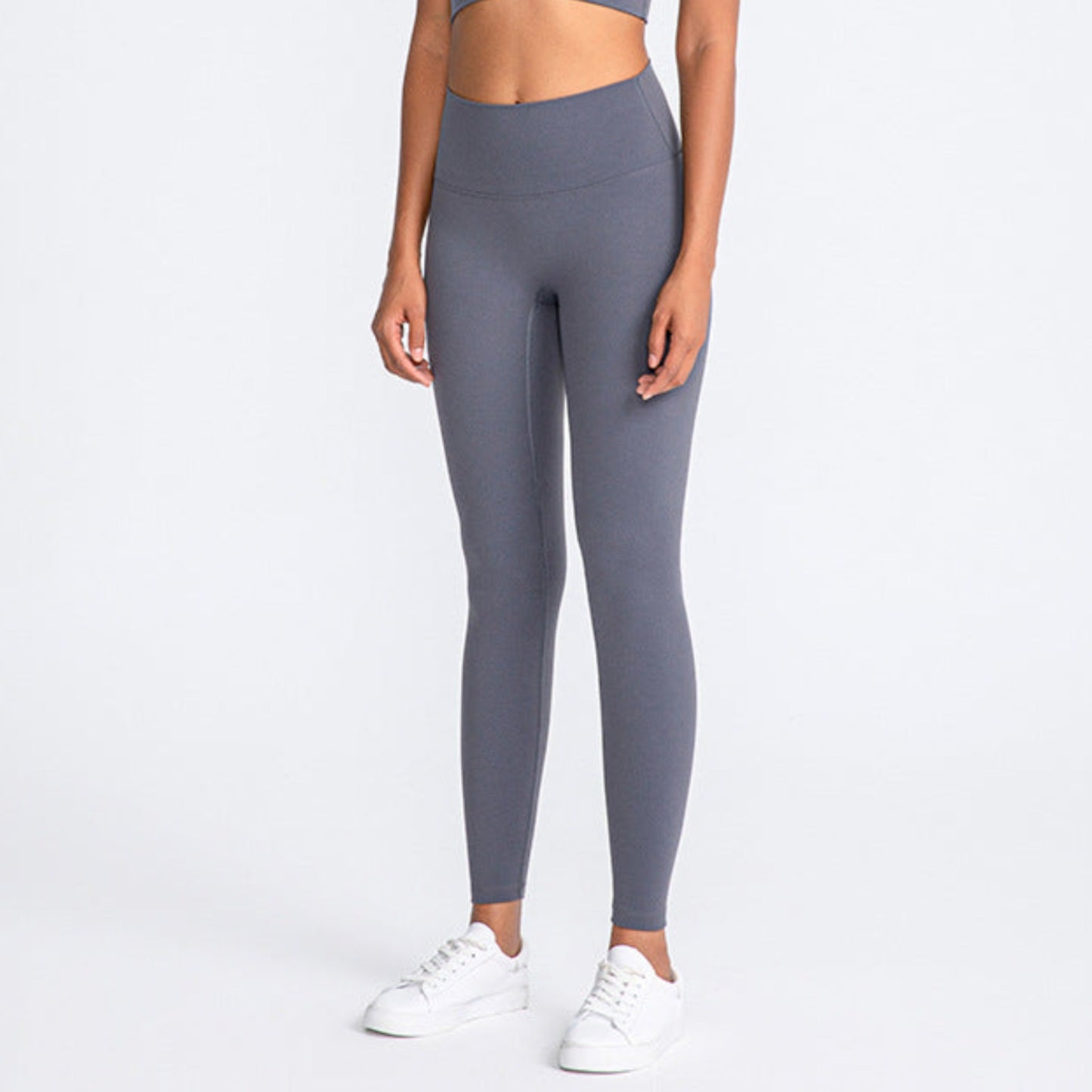 ASH GREY, HIGH RISE AND SQUAT PROOF LEGGINGS WORN BY MODEL ON A WHITE BACKGROUND