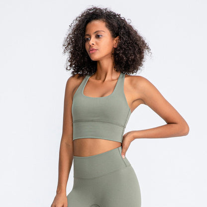 african american woman posing in a white background wearing a olive sports bra and workout pants from Vibras Activewear